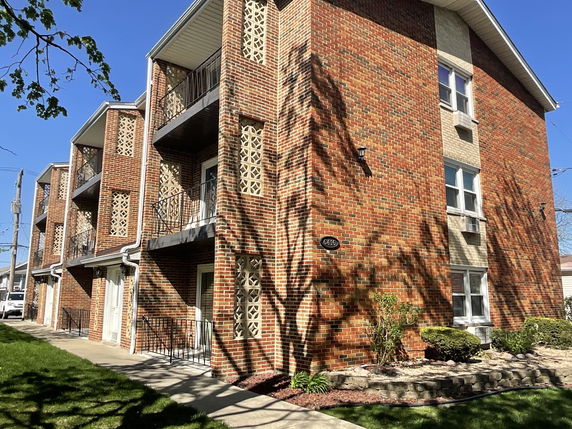Front view of a brick apartment building with multiple balconies.