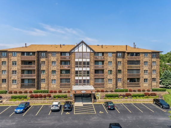 Front view of a multi-story apartment building with parking area.