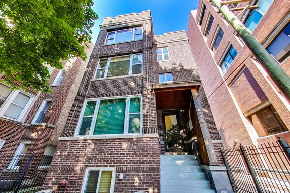 Front view of a multi-story brick building with large windows and a staircase leading to the entrance.