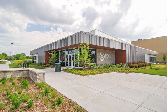 Front view of a modern single-story building with large glass windows and a metal facade.