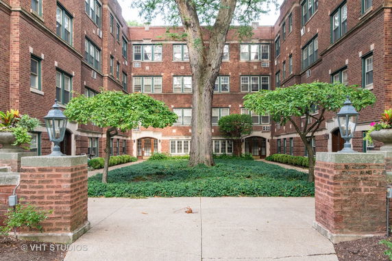 Front view of a brick apartment building with landscaped courtyard.
