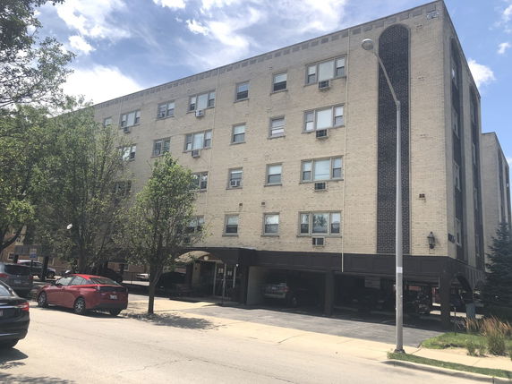 Front view of a multi-story apartment building with covered parking.