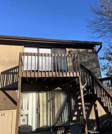 Front view of a two-story house with a balcony and exterior stairs.