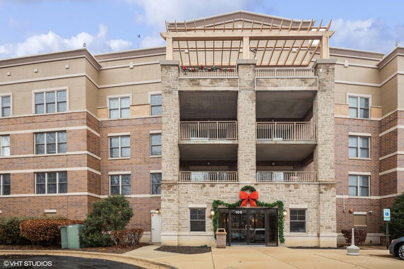 Front view of a multi-story building with brick and stone facade, featuring balconies and a decorative entrance.