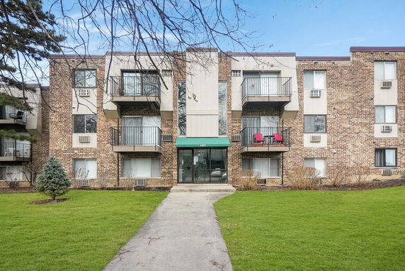 Front view of a multi-story brick apartment building with balconies.