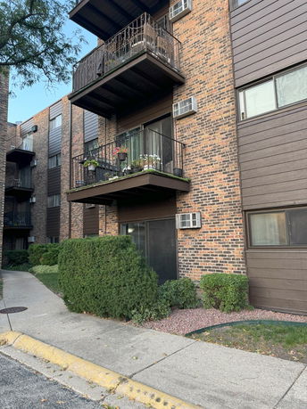 Front view of a multi-story brick apartment building with balconies.