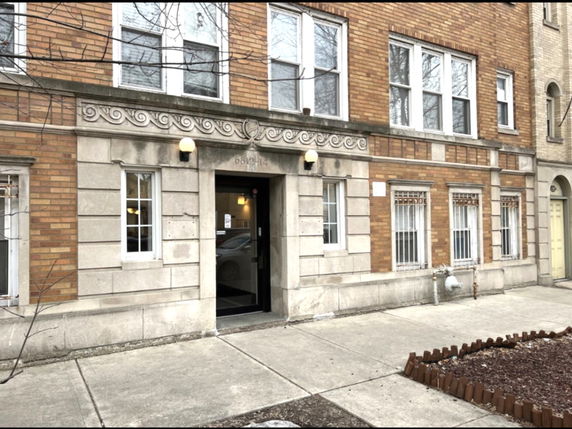 Front view of a multi-story brick building with decorative stone elements.