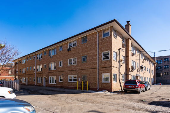Front view of a three-story brick apartment building with multiple windows.