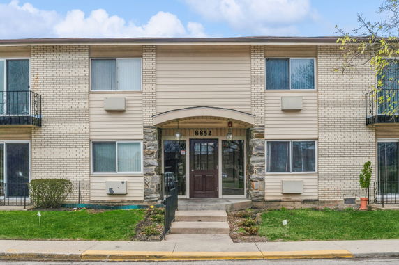Front view of a two-story residential building with balconies and a central entrance.