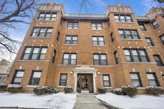 Front view of a multi-story brick building with numerous windows and an entrance.