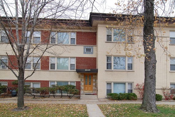 Front view of a multi-story brick apartment building with a central entrance.