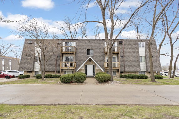 Front view of a three-story apartment building with a unique roof design and multiple small balconies.