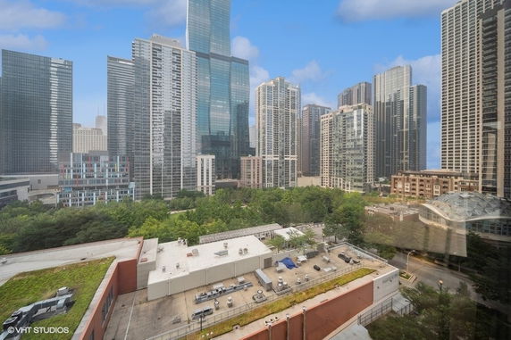 Panoramic view of city skyline with tall buildings and a rooftop in the foreground.