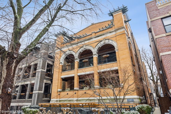 Front view of a three-story building with arched balconies and brick facade.