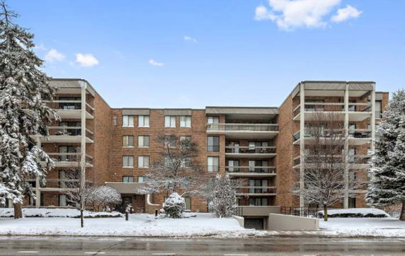 Front view of a multi-story brick apartment building with balconies in a snowy landscape.