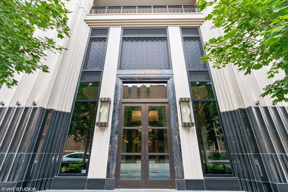 Front view of a building entrance with large glass doors and decorative metalwork.