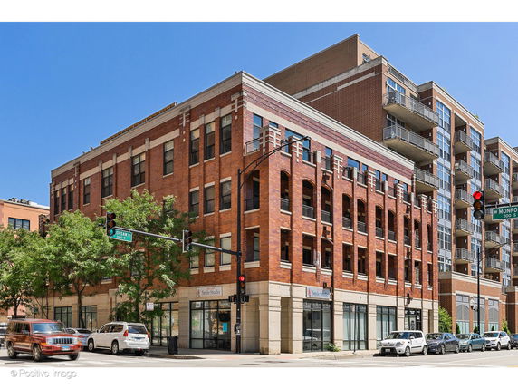 Front view of a multi-story brick building with large windows on an urban street.