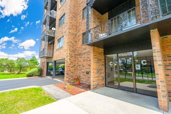 Front view of a multi-story brick building with balconies and entrance.
