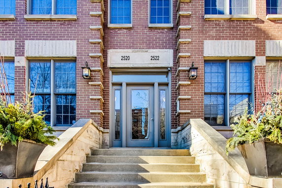 Front view of a brick building entrance with steps leading up to a door.