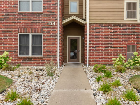 Front view of a building entrance with brick facade and a pathway leading to the door.