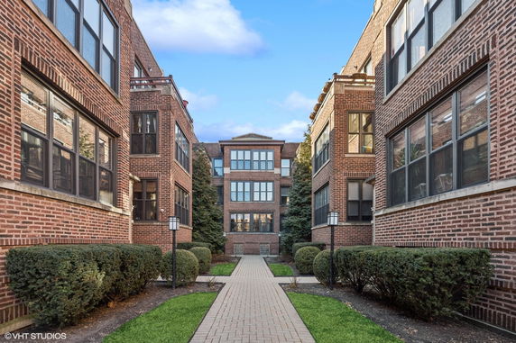 Front view of a multi-story brick apartment building with large windows.