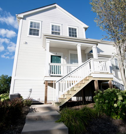 Front view of a two-story house with white siding and a green door.
