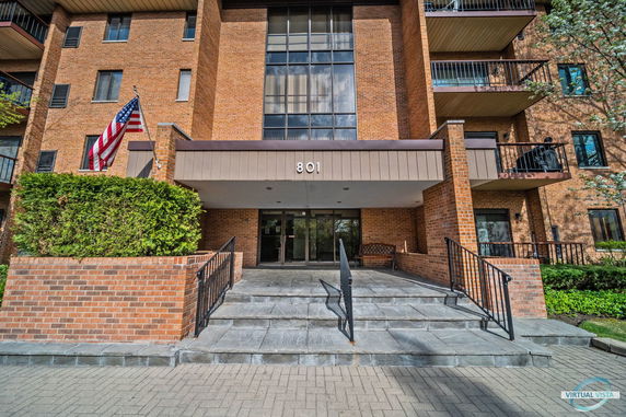 Front view of a multi-story brick building with entry stairs and balconies.
