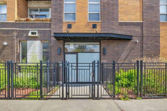 Front view of a multi-story building with brick facade and entrance gate.