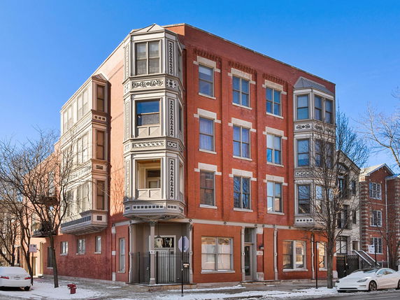 Front view of a three-story brick building with decorative trim and large windows.