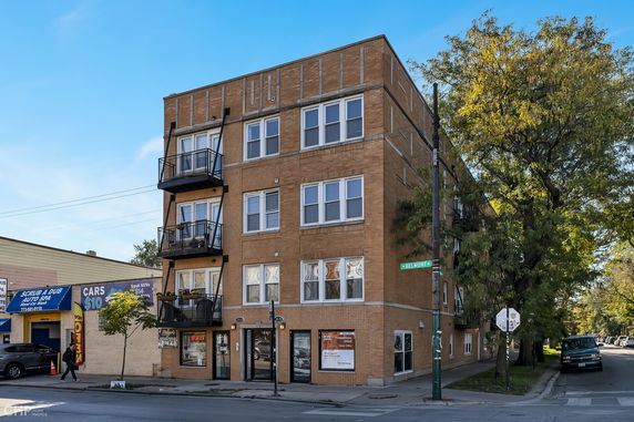 Front view of a multi-story brick building on a street corner.