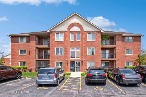 Front view of a three-story brick apartment building with balconies.