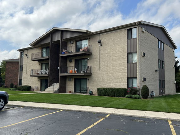 Front view of a three-story apartment building with balconies.