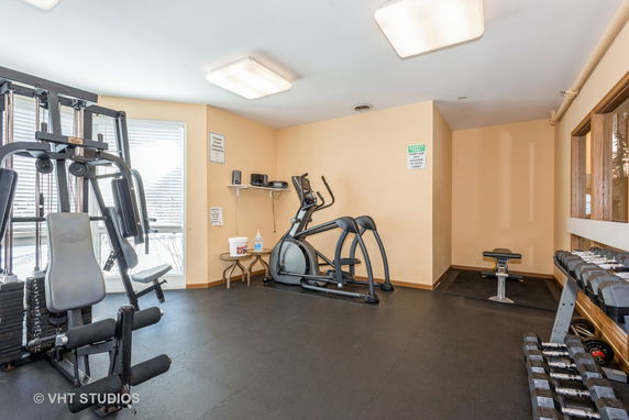 Indoor gym area with exercise equipment including weights and machines.