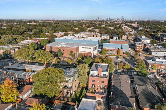 Aerial panoramic view of an urban area with buildings, trees, and a distant city skyline.