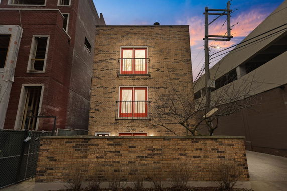 Front view of a brick facade building with two floors and red window frames.