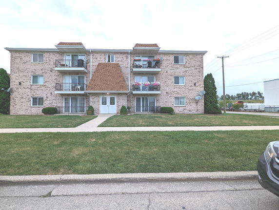 Front view of a three-story apartment building with balconies.