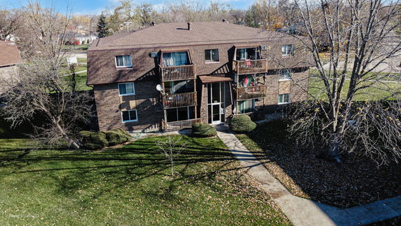 Front view of a multi-story brick apartment building with balconies.