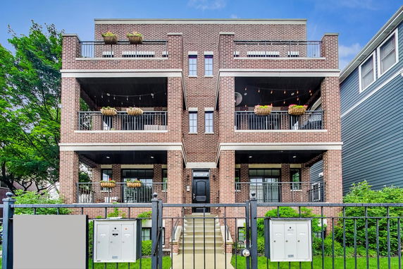 Front view of a multi-story brick building with balconies and planters.