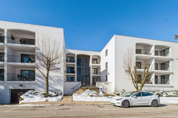 Front view of a multi-story apartment building with balconies and a central entrance.