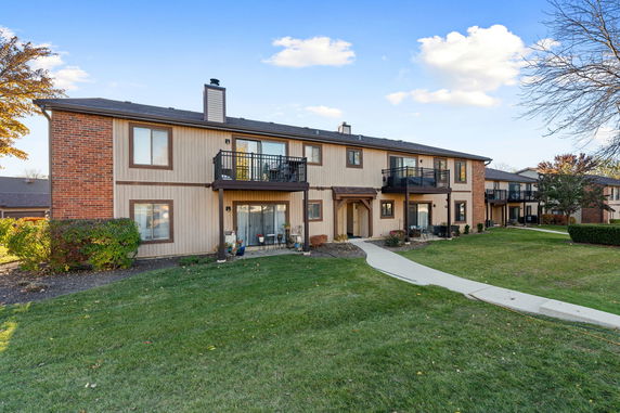 Front view of a two-story townhouse building with balconies and a sidewalk.