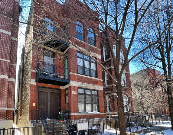 Front view of a multi-story brick apartment building with balconies.