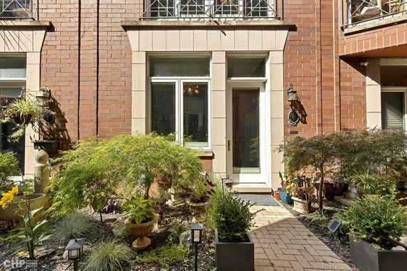 Front view of a brick house entrance with a pathway and plants.