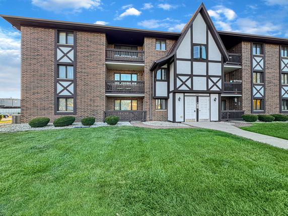 Front view of a multi-story brick building with wooden accents and balconies.
