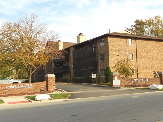Front view of a multi-story brick apartment building with balconies.