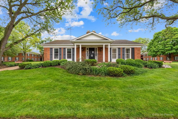 Front view of a single-story brick house with pillars and a gabled roof.