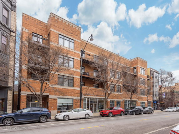 Front view of a multi-story apartment building with a brick facade and balconies.