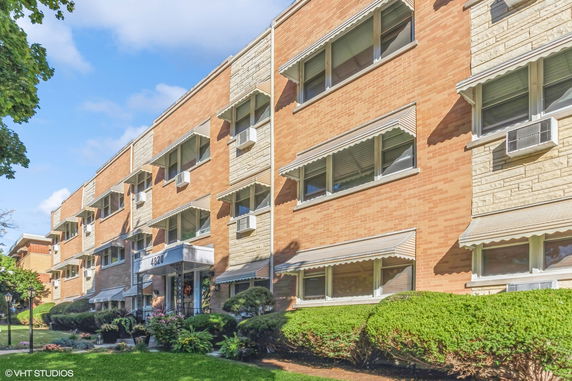 Front view of a multi-story brick apartment building with a central entrance.