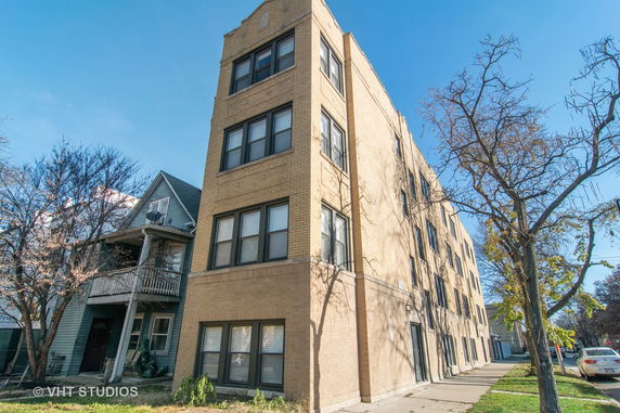 Front view of a multi-story brick apartment building with multiple windows.
