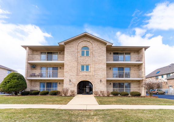Front view of a three-story apartment building with balconies.