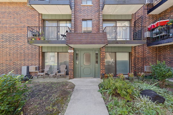 Front view of a brick multi-story building with balconies and a green entrance door.